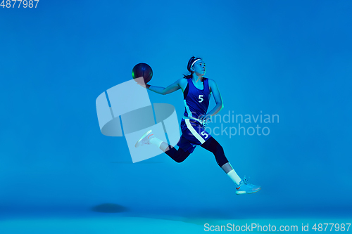 Image of Young caucasian female basketball player isolated on blue studio background in neon light