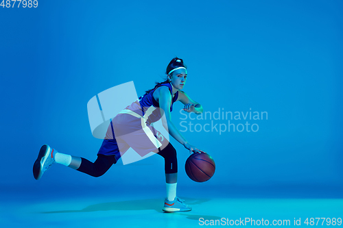 Image of Young caucasian female basketball player isolated on blue studio background in neon light