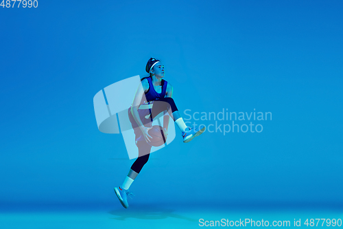 Image of Young caucasian female basketball player isolated on blue studio background in neon light