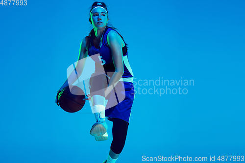 Image of Young caucasian female basketball player isolated on blue studio background in neon light