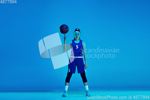 Image of Young caucasian female basketball player isolated on blue studio background in neon light