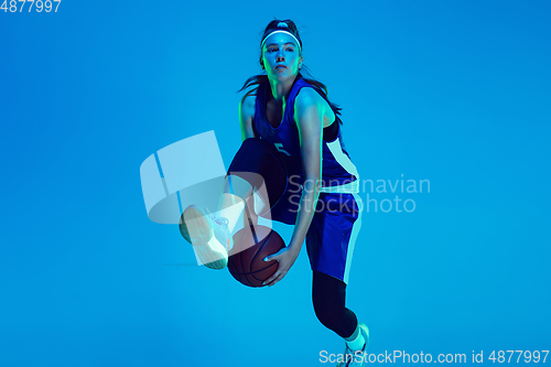 Image of Young caucasian female basketball player isolated on blue studio background in neon light