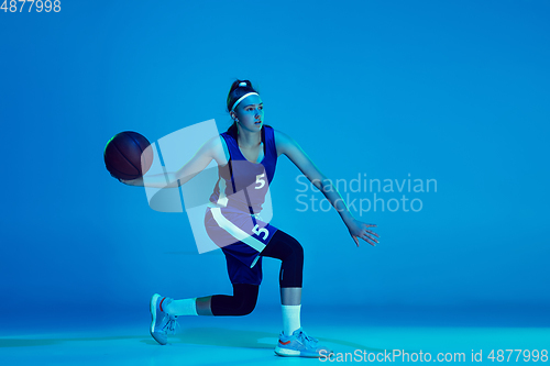 Image of Young caucasian female basketball player isolated on blue studio background in neon light