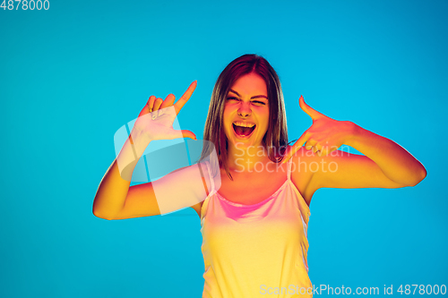 Image of Caucasian young woman\'s portrait isolated on blue background in neon light