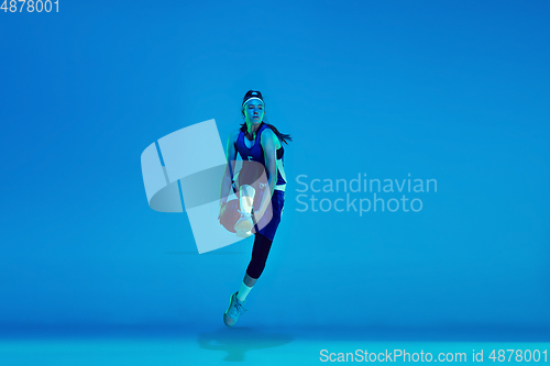 Image of Young caucasian female basketball player isolated on blue studio background in neon light