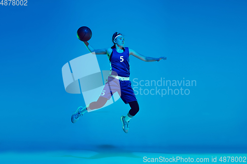 Image of Young caucasian female basketball player isolated on blue studio background in neon light