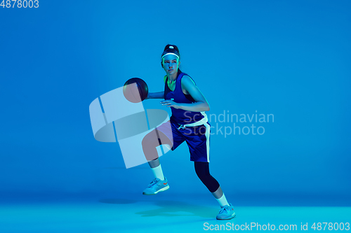 Image of Young caucasian female basketball player isolated on blue studio background in neon light