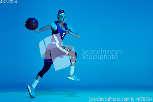 Image of Young caucasian female basketball player isolated on blue studio background in neon light
