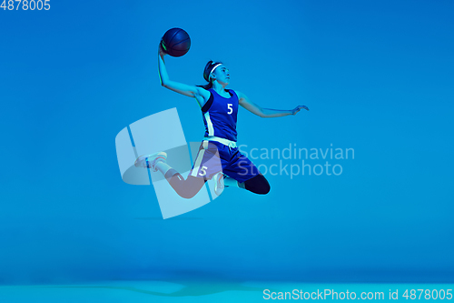 Image of Young caucasian female basketball player isolated on blue studio background in neon light