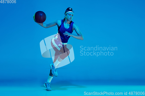 Image of Young caucasian female basketball player isolated on blue studio background in neon light