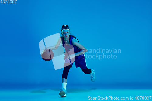 Image of Young caucasian female basketball player isolated on blue studio background in neon light