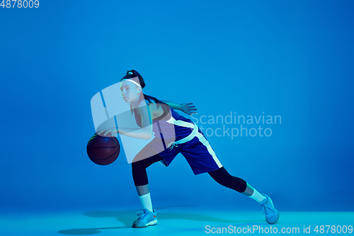 Image of Young caucasian female basketball player isolated on blue studio background in neon light