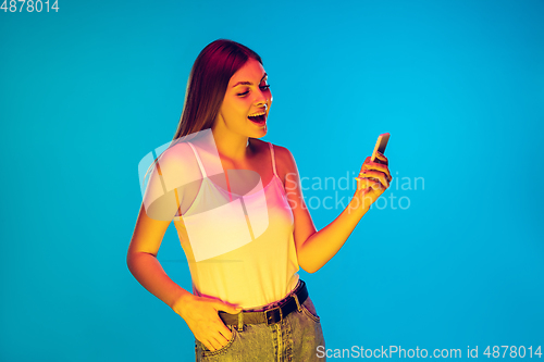 Image of Caucasian young woman\'s portrait isolated on blue background in neon light
