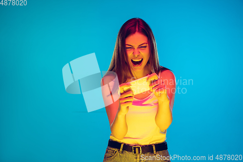 Image of Caucasian young woman\'s portrait isolated on blue background in neon light