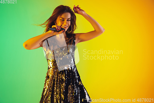 Image of Caucasian female singer portrait isolated on gradient studio background in neon light