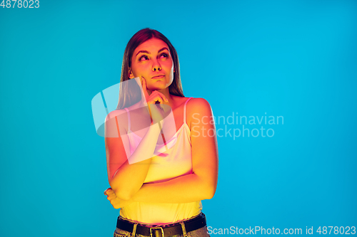 Image of Caucasian young woman\'s portrait isolated on blue background in neon light