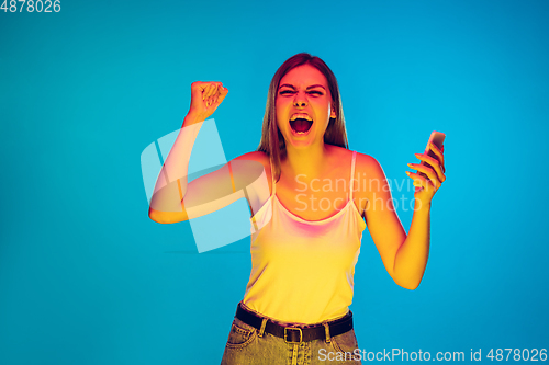 Image of Caucasian young woman\'s portrait isolated on blue background in neon light
