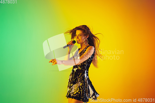 Image of Caucasian female singer portrait isolated on gradient studio background in neon light