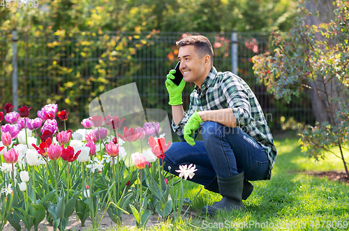 Image of man with flowers calling on smartphone at garden