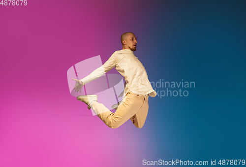 Image of Stylish sportive caucasian man dancing hip-hop on colorful gradient background at dance hall in neon light.