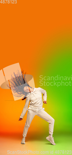 Image of Stylish sportive caucasian woman dancing hip-hop on colorful gradient background at dance hall in neon light.