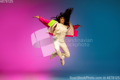 Image of Stylish sportive caucasian woman dancing hip-hop on colorful gradient background at dance hall in neon light.