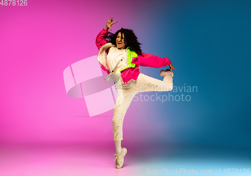 Image of Stylish sportive caucasian woman dancing hip-hop on colorful gradient background at dance hall in neon light.