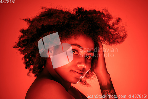 Image of Beautiful african-american woman portrait isolated on red studio background in neon light, monochrome