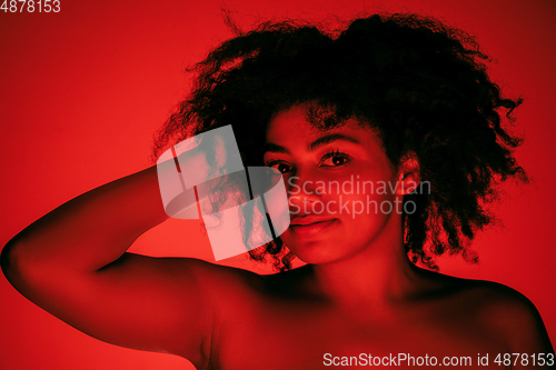 Image of Beautiful african-american woman portrait isolated on red studio background in neon light, monochrome