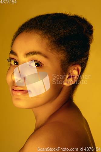 Image of Beautiful african-american woman portrait isolated on yellow studio background in neon light, monochrome