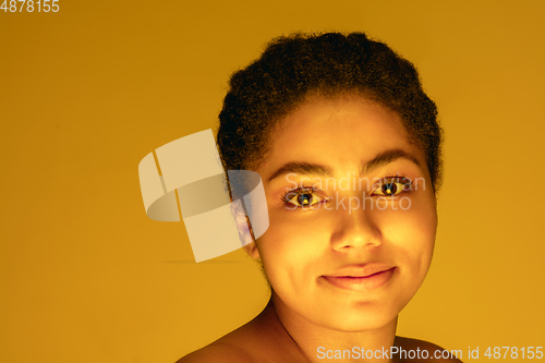 Image of Beautiful african-american woman portrait isolated on yellow studio background in neon light, monochrome