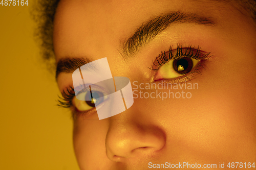 Image of Beautiful african-american woman portrait isolated on yellow studio background in neon light, monochrome