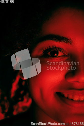 Image of Beautiful african-american woman portrait isolated on red studio background in neon light, monochrome