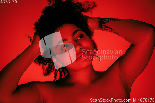 Image of Beautiful african-american woman portrait isolated on red studio background in neon light, monochrome