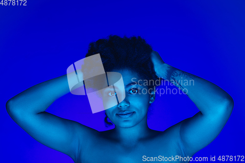 Image of Beautiful african-american woman portrait isolated on blue studio background in neon light, monochrome