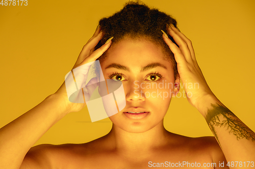 Image of Beautiful african-american woman portrait isolated on yellow studio background in neon light, monochrome