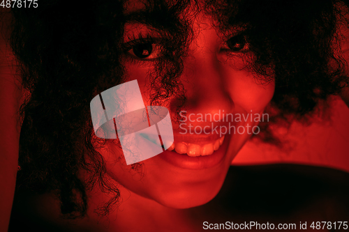 Image of Beautiful african-american woman portrait isolated on red studio background in neon light, monochrome