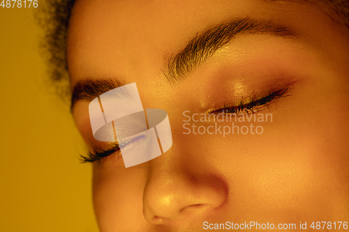 Image of Beautiful african-american woman portrait isolated on yellow studio background in neon light, monochrome