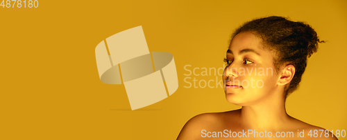 Image of Beautiful african-american woman portrait isolated on yellow studio background in neon light, monochrome