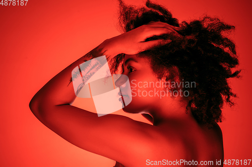 Image of Beautiful african-american woman portrait isolated on red studio background in neon light, monochrome