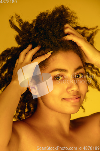 Image of Beautiful african-american woman portrait isolated on yellow studio background in neon light, monochrome