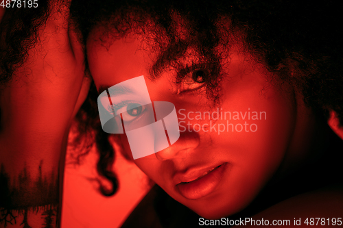 Image of Beautiful african-american woman portrait isolated on red studio background in neon light, monochrome