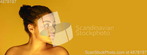 Image of Beautiful african-american woman portrait isolated on yellow studio background in neon light, monochrome