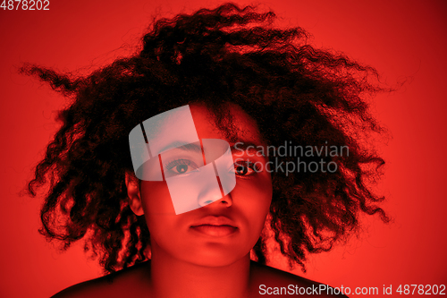 Image of Beautiful african-american woman portrait isolated on red studio background in neon light, monochrome