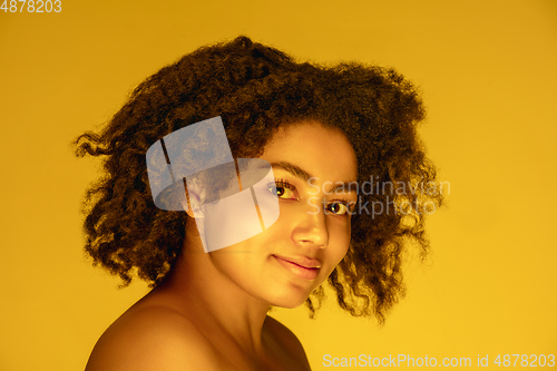 Image of Beautiful african-american woman portrait isolated on yellow studio background in neon light, monochrome