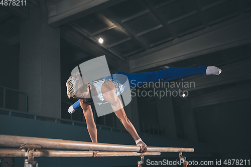 Image of Little male gymnast training in gym, flexible and active. Caucasian fit little boy, athlete in sportswear practicing in exercises for strength, balance.