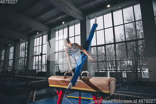 Image of Little male gymnast training in gym, flexible and active. Caucasian fit little boy, athlete in sportswear practicing in exercises for strength, balance.