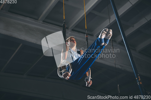 Image of Little male gymnast training in gym, flexible and active. Caucasian fit little boy, athlete in sportswear practicing in exercises for strength, balance.