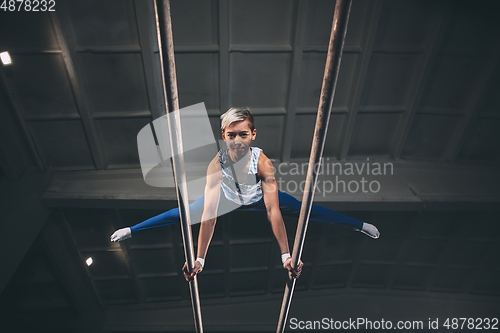 Image of Little male gymnast training in gym, flexible and active. Caucasian fit little boy, athlete in sportswear practicing in exercises for strength, balance.