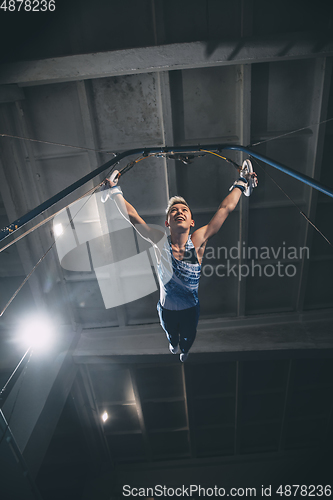 Image of Little male gymnast training in gym, flexible and active. Caucasian fit little boy, athlete in sportswear practicing in exercises for strength, balance.